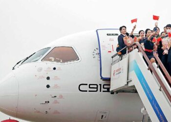 Crew members wave Chinese national flags out of a Commercial Aircraft Corp of China (COMAC) C919 aircraft, China’s first domestically produced large passenger jet, after landing at Hongqiao International Airport as it is formally handed over to China Eastern Airlines in Shanghai on 9 December – AFP